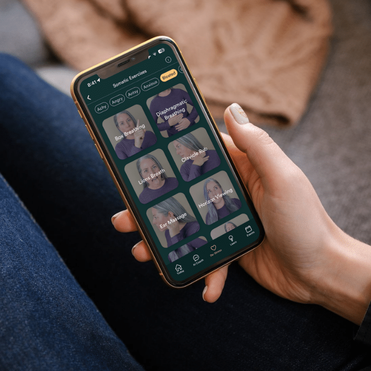 Hand holding a smartphone displaying a somatic exercise app with tiles for breathing techniques like Box Breathing and Diaphragmatic Breathing